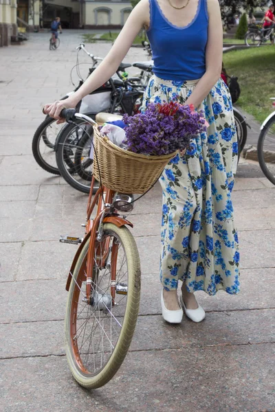 Kobieta w kolorowej spódnicy trzyma koło roweru. — Zdjęcie stockowe