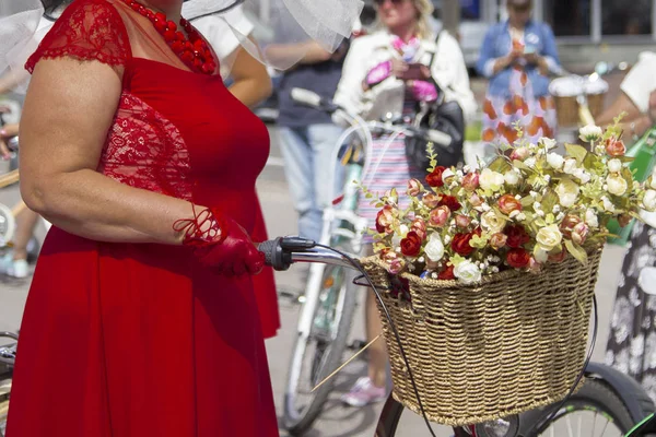 Mujer con un vestido rojo y guantes sostiene la rueda de la bicicleta . — Foto de Stock