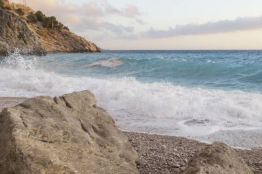 Kıyıdaki kayalıklarda dalgalar kopuyor.