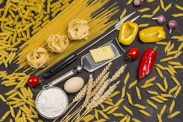 Organic food  on black background. Variety of types and shapes of dry pasta
