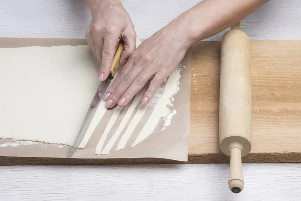 Рука розрізає ручне тісто на смужки ножем . — стокове фото