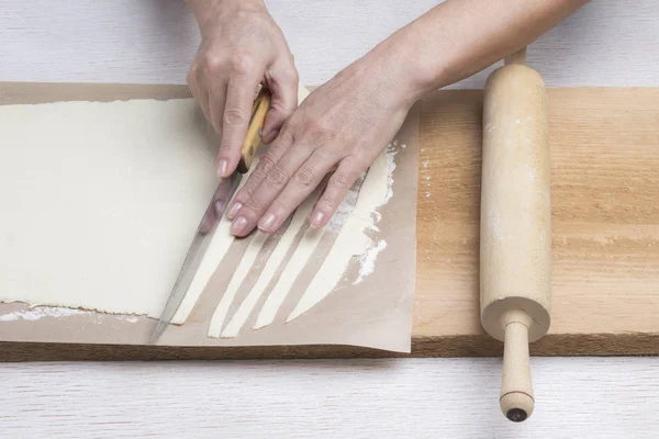 Coupe à la main la pâte roulée en lanières avec couteau . — Photo