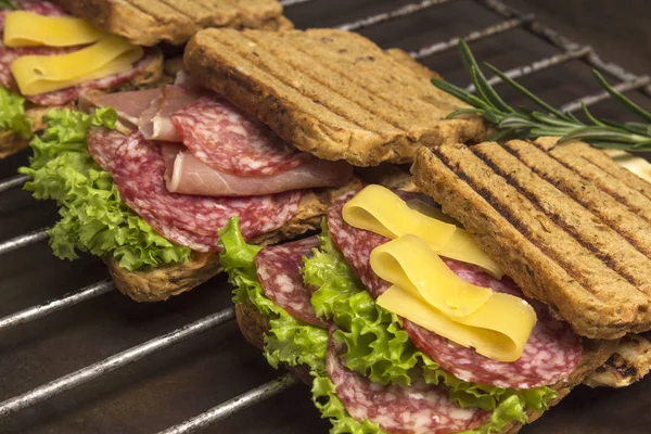 Sandwiches a la parrilla con salami, queso y ensalada a la parrilla de metal — Foto de Stock