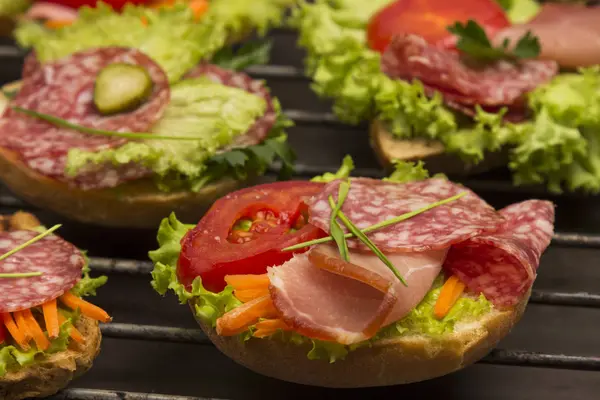 Sanduíches com carne e verduras, pão com grãos em grelha metálica . — Fotografia de Stock