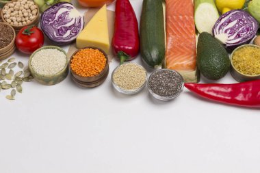 Dengeli beslenme için sağlıklı besinler: somon, peynir, sebze, fasulye, fındık, kinoa, bulgur, nohut, keten, badem. Omega-3 ve protein kaynakları. Düz yerde, üst tarafta. Beyaz arka plan. Boşluğu kopyala