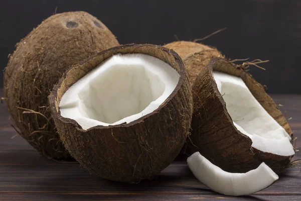 Kokosový ořech, nakrájený na půl kokosu na tmavém dřevěném pozadí — Stock fotografie