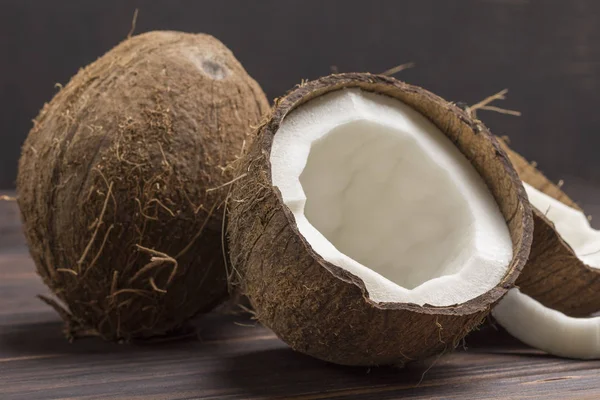 Kokosový ořech, nakrájený na půl kokosu na tmavém dřevěném pozadí — Stock fotografie