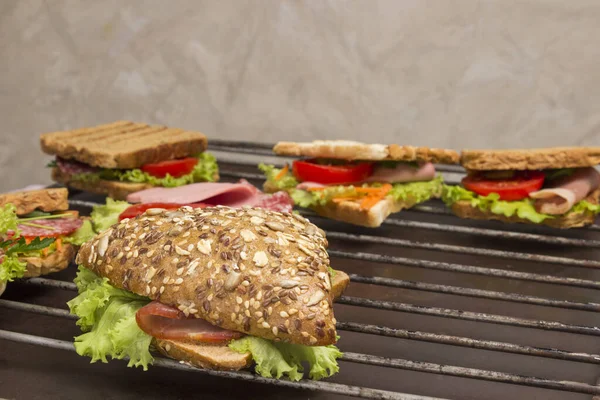 Grilled sandwich with bacon, salami, cheese and salad on metal grill. Outdoor food concept. top view, close up, copy space