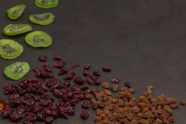 Candied Kiwi Raisins Dried Cranberries, natural source of energy. Health food fitness.  Black background. Flat lay