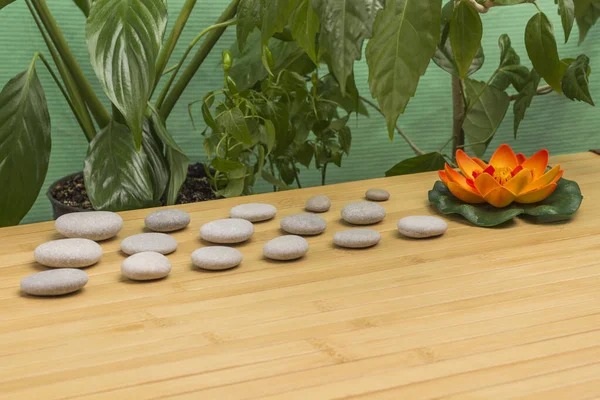 Candle and spa stones, orange lily with green leaves. Relax concept. Wooden background