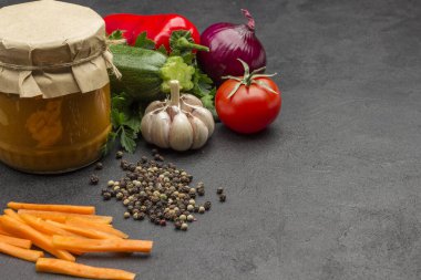 Cam kavanoza yayılmış kabak konservesi. Çiğ sebze ve baharat: havuç sarımsak, soğan domates, yıldız anason, acı biber, maydanoz. Sağlıklı kış besinleri. Fermantasyon Ürünleri. Siyah arkaplan