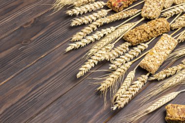 Tahıl gevreği enerji granola çubukları ve koyu ahşap arka planda buğday dikenleri. Dengeli protein kahvaltısı. Üst Manzara. Boşluğu kopyala