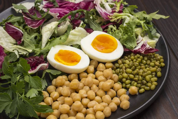 Multicolored vegetable mix, chickpeas, mung bean. Vegan food. Clean eating. Flat lay. Dark background.