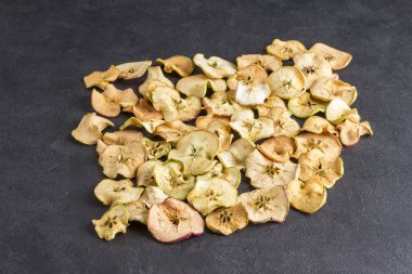 Siyah arka planda kurumuş elma dilimleri. Sağlıklı beslenme atıştırmalığı. Boşluğu kopyala