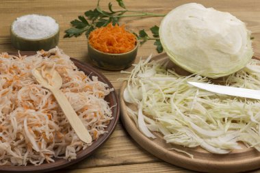 Havuç ve tuzlu lahana tabakta. Dilimlenmiş çiğ lahana, kesme tahtasında bıçak. Ev yapımı Fermantasyon Ürünleri. Kapat.