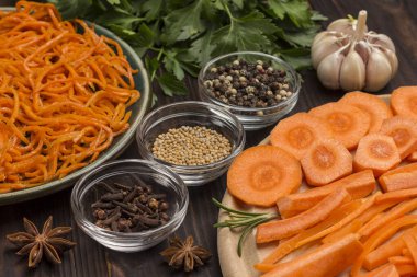 Baharat, sarımsak ve maydanoz. Kesme tahtasında çiğ havuç. Tabakta mayalanmış havuç. Doğal soğuk algınlığı ilacı. Yakın plan. Koyu tahta arkaplan