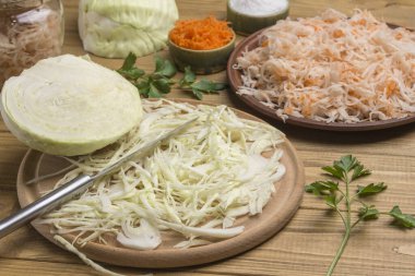 Tabakta lahana turşusu, dilimlenmiş çiğ lahana, kesme tahtasında bıçak, yarım lahana kafası. Ev yapımı Fermantasyon Ürünleri. Kapat.