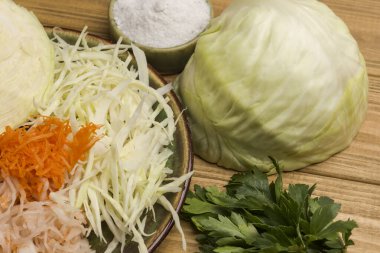 Dilimlenmiş çiğ lahana, yarım lahana kafa, tuz, yeşil maydanoz. Sağlıklı diyet yemekleri. Kapat.