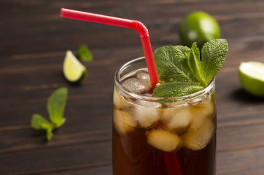 Buzlu ve naneli soğuk yaz çayı. Masanın üzerinde kireç ve nane yaprakları var. Karanlık ahşap arka plan. Kapat.