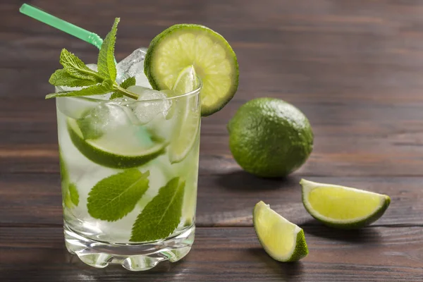 Summer cooling drink with ice, lime and mint. Non-alcoholic beverage. Dark wooden background. Close up