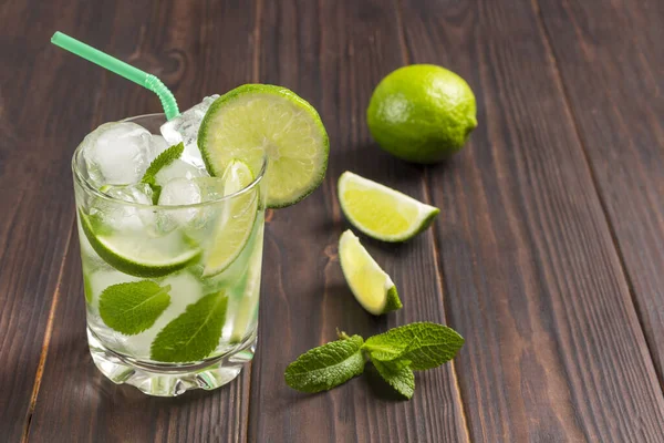 Summer cooling drink with ice, lime and mint. Non-alcoholic beverage. Dark wooden background. Copy space. Top view