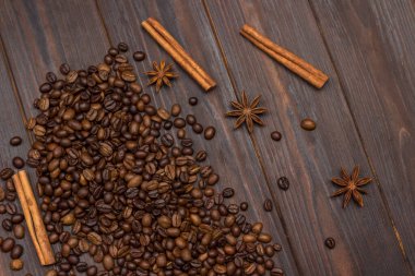 Masaya dağılmış kahve çekirdekleri, yıldız anason, tarçın çubukları. Karanlık arka plan. Düz yatıyordu