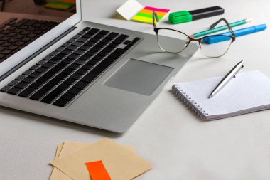 Laptop, defter ve kalem, bardaklar, kırtasiye malzemeleri masada. Evden çalışıyorum. Beyaz arkaplan.