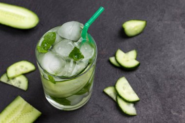 Buzlu ve salatalıklı serinletici yaz içeceği. Siyah arka planda nane ve doğranmış salatalık. Kapatın. Üst görünüm. 