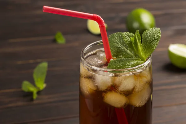 Cooling summer tea with ice and mint. Red straw in glass. Close up