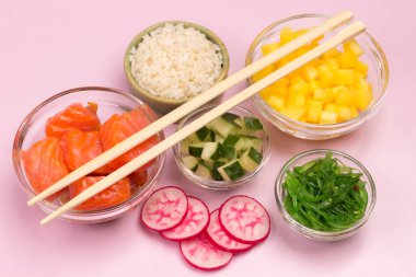 Tavada nane ve biberiye ile doğranmış nehir balığı. Masada domates, limon ve cam şişe yağ var. Siyah arka plan. Üst görünüm