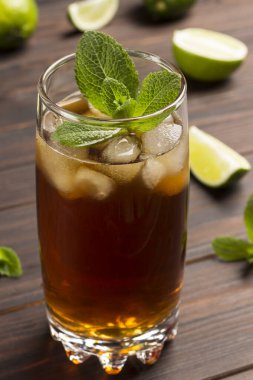 Buzlu ve naneli soğuk yaz çayı. Masa kireç ve nane yapraklarının üzerinde. Karanlık ahşap arka plan. Kapat.