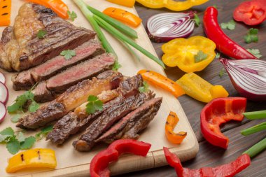 Tahta tahtada sebze ve orta pişmiş mermer biftek. Taze ızgara et. Doğal protein kaynağı. Üst Manzara. Kapat.