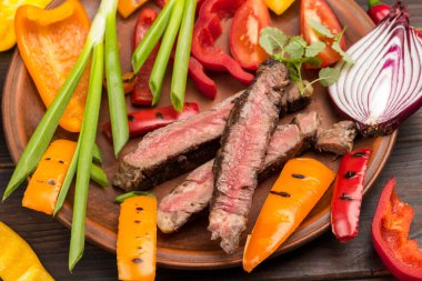 Tabakta dilimlenmiş mermer biftek. Sebzeler masada. Organik yiyecekler. Üst Manzara. Kapatın. Koyu Ahşap arkaplan