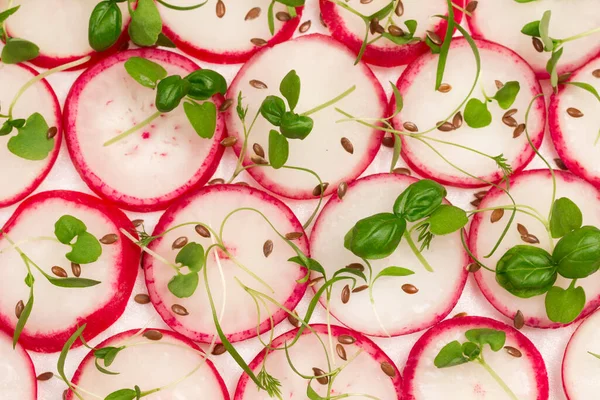 Sliced radish and flaxseeds with young microgreen sprouts, healthy nutrition. Close up. Flat lay. White background