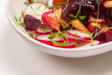 Dilimlenmiş haşlanmış pancar, dilimlenmiş turp ve taze mikroyeşil lahanalı elmalardan oluşan besleyici bir salata. Uzayı kopyala Beyaz arkaplan