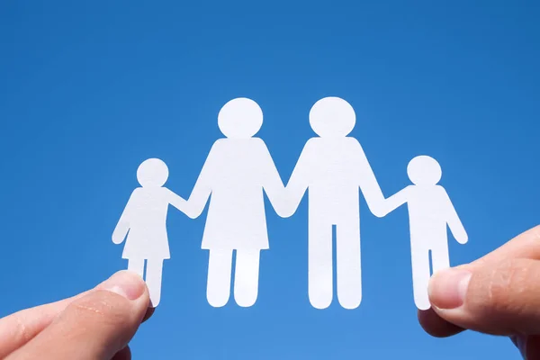 Familia de papel en dos manos sobre un fondo azul del cielo — Foto de Stock