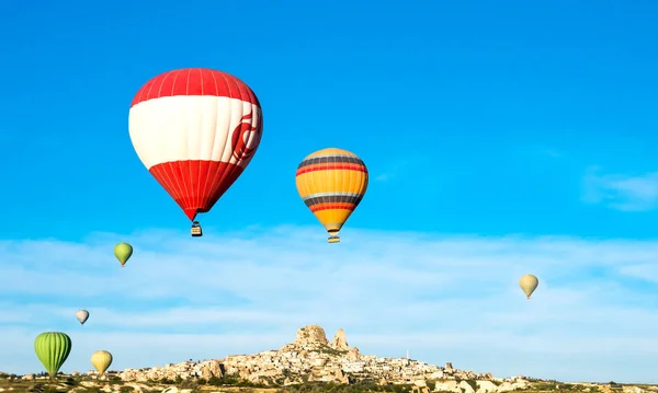 Πολύχρωμα αερόστατα που φέρουν κοντά στο κάστρο του Uchisar στην Ανατολή του ηλίου — Φωτογραφία Αρχείου