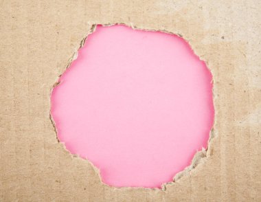 Karton pembe bir arka plan üzerinde delik yırtık
