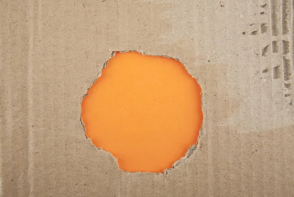 Trou déchiré en carton sur fond orange — Photo