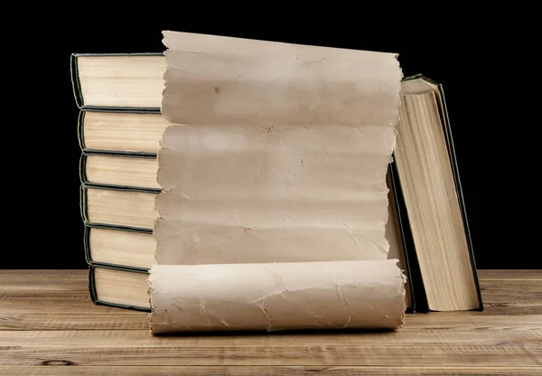 Libros antiguos y papel viejo sobre una mesa de madera aislada sobre una ba negra — Foto de Stock