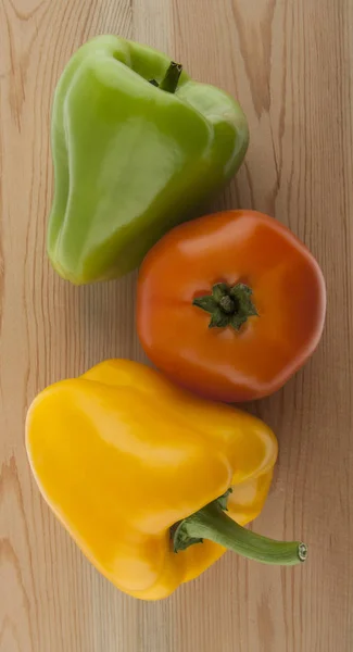 Papriky a rajčata na dřevěný stůl — Stock fotografie