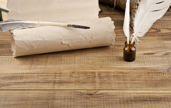 Old paper and feather with ink on a wooden table