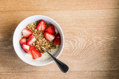 Sağlıklı kahvaltı - yoğurtlu müsli ve beyaz kasede çilekli