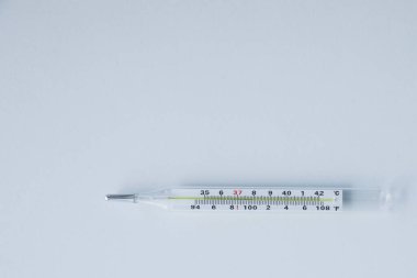 Beyaz zemin üzerinde beyaz bir kağıt tabakası bulunan termometre.