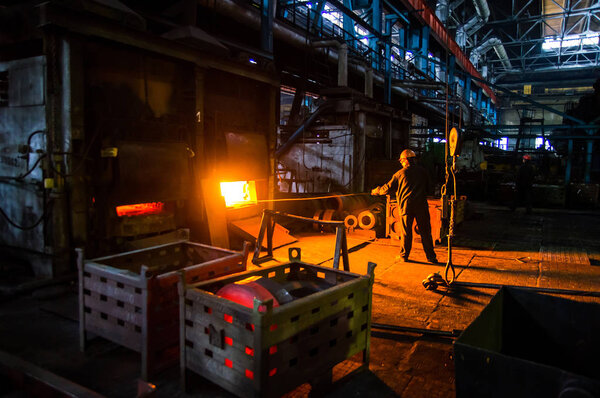 работник вытаскивает заготовку из печи
