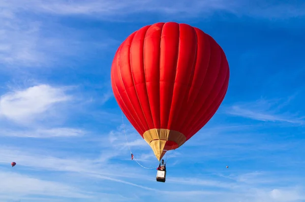 Czerwony balon na gorące powietrze przeciwko błękitnemu, pochmurnemu niebu. — Zdjęcie stockowe