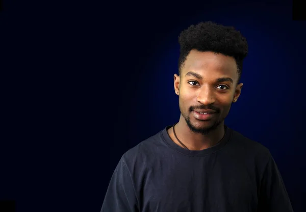 Giovane uomo nero in t-shirt su sfondo nero e blu — Foto Stock