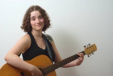 genç kadın beyaz gri arka plan üzerinde gitar çalmak