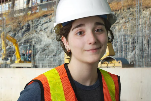 Flicka på byggarbetsplatsen med orange väst och vit säkerhet hatt — Stockfoto