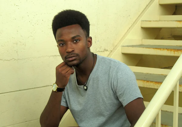 Afrikaanse zwarte jongeman zitten in de trap — Stockfoto